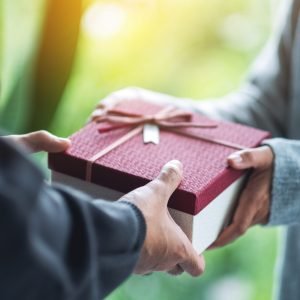 Closeup image of a man giving a woman a gift box